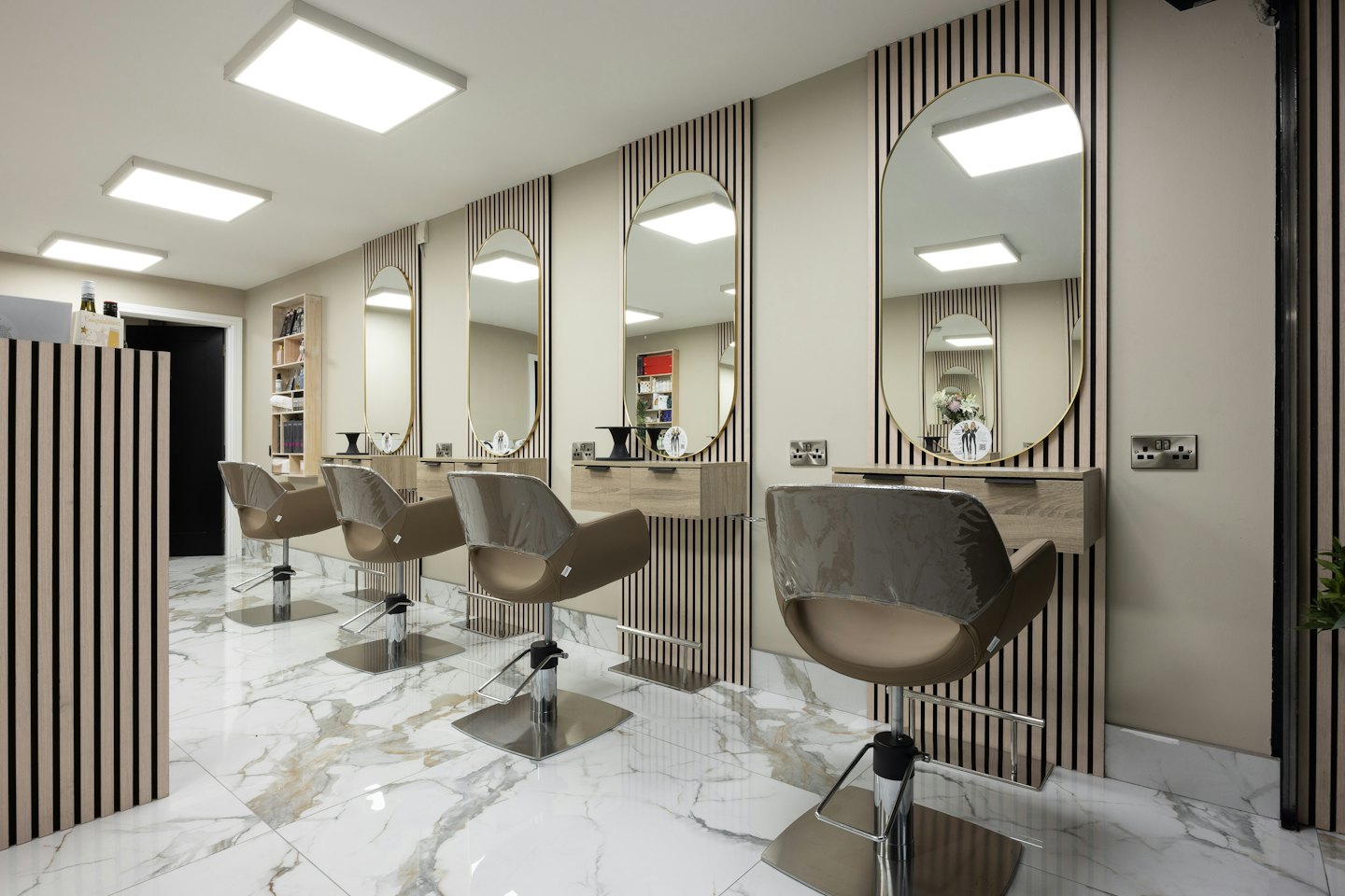 Contemporary hair salon styling stations with gold mirrors and wood cabinets.