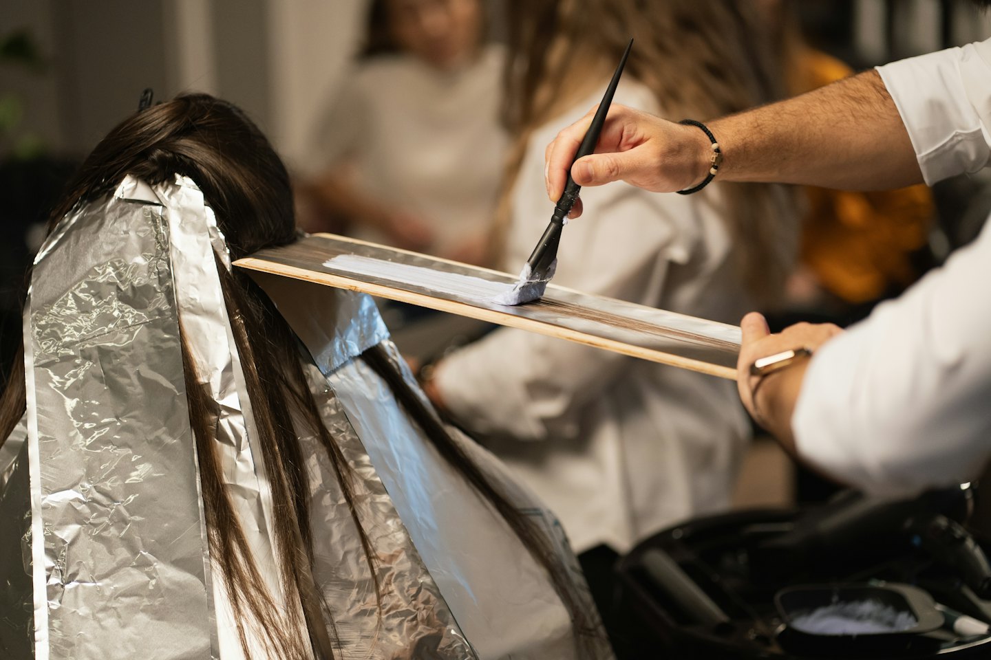 Hair stylist applying hair dye to a client's hair in a salon.