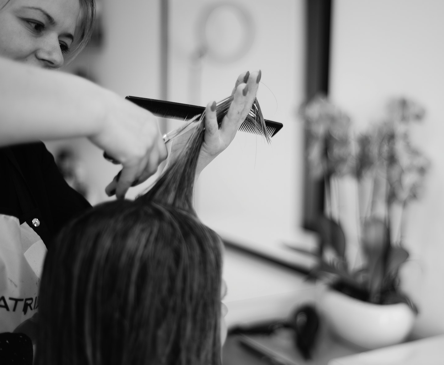 Hairstylist cutting a client's long hair with scissors.